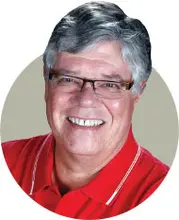 Smiling man with glasses wearing a red polo shirt.