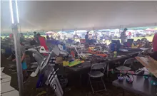 Large tent with people assembling model planes on tables.