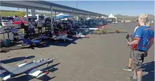 People observing model airplanes on display under a tented area at an outdoor event.