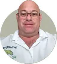 Man in glasses wearing a white polo shirt with text and logo on it.