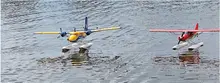Two model seaplanes, one yellow and blue, one red, on water.