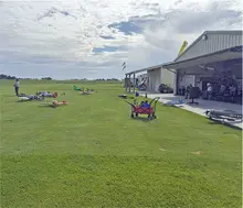 Model airplanes on grass field near a hangar under a cloudy sky.