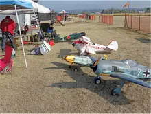 Model airplanes displayed on grassy field at a small airshow.